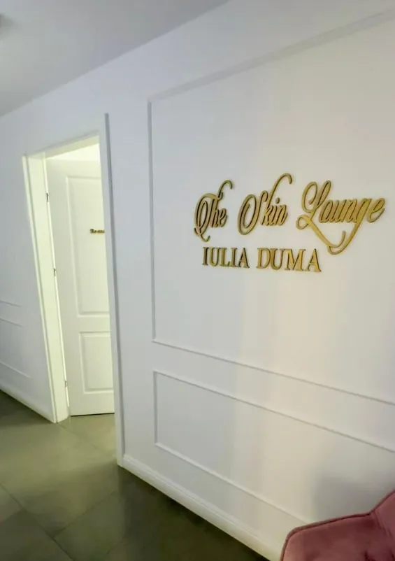 Inscripția aurie „The Skin Lounge, Iulia Duma” pe peretele de la intrare